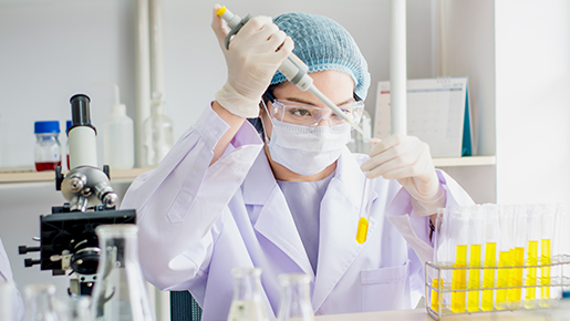 Woman with yellow liquid in vials and microscope